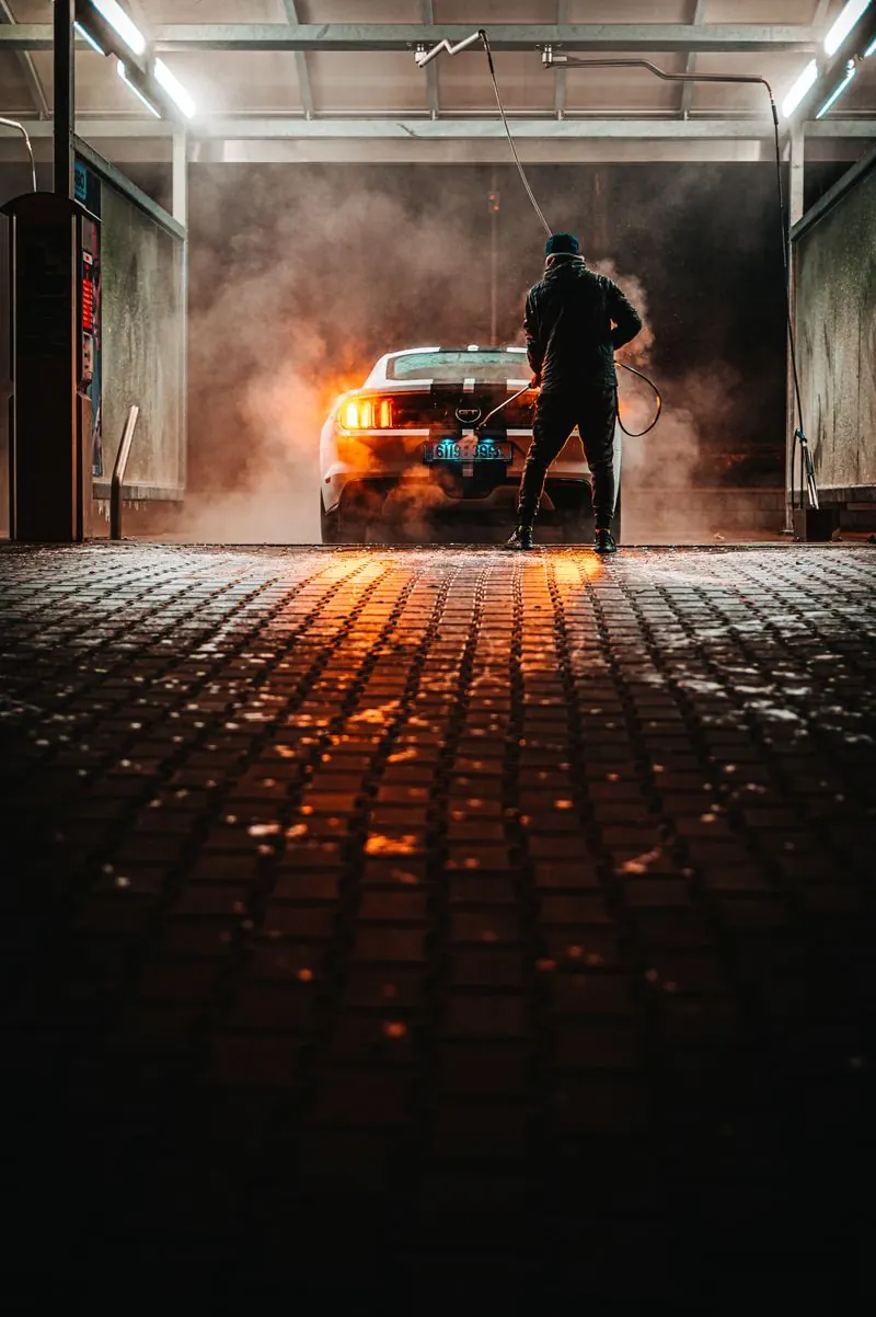 Detailer au travail dans un garage avec de la vapeur et un éclairage orangé