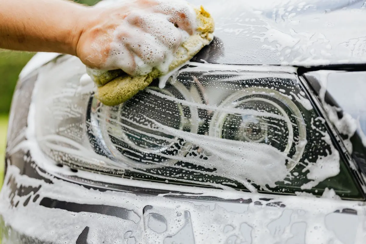 Lavage à la main d'un phare de voiture avec de la mousse